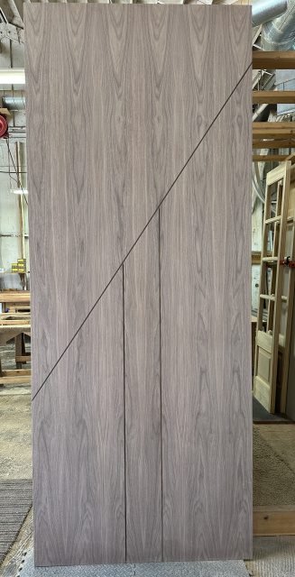 Walnut flush door with bold diagonal line crossing vertical reveals — project 031 by Whitebird Woodcraft