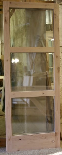 Unfinished knotty Alder door with three tall stacked glass lites in classic vertical arrangement — project 032 by Whitebird Woodcraft