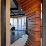 Morpheus Door pivoted open into a modern living space with sheer curtains and dark wood floors. Project 035 by Whitebird Woodcraft